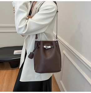Detail of brown leather bucket bag with silver twist lock and lychee grain texture