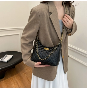 Sac matelassé noir avec chaîne dorée porté par un mannequin en tenue chic