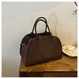 Macro detail of dark brown suede tote bag with golden buckle and sturdy handles