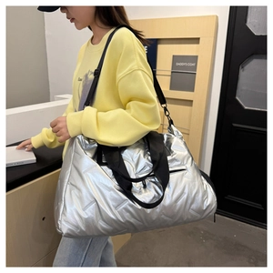 Silver quilted sports bag worn crossbody by a model showing its large capacity and style