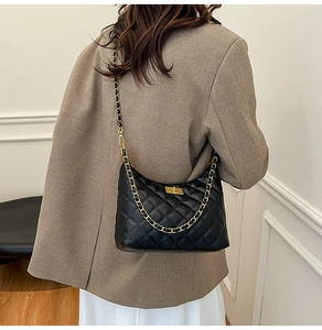 Détail du sac matelassé noir à losanges avec chaîne dorée et fermoir pivotant
