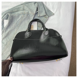 Detail of black leather tote bag featuring contrast white stitching and gold base studs