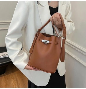 Close-up of brown litchi pattern bucket bag with silver lock and adjustable strap