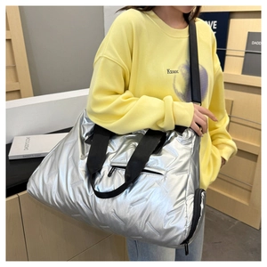 Detail of silver quilted gym bag with metallic finish and black adjustable shoulder strap