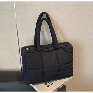 Detail of black quilted puffer tote bag showing smooth zipper and thick padded handles