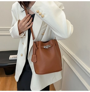 Detailed view of brown lychee grain leather bucket bag with silver twist lock and strap