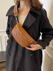 Brown lychee leather saddle bag with double zipper pockets and striped crossbody strap