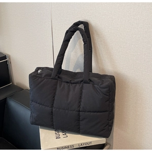 Detail of black quilted tote bag with smooth metal zipper and water-resistant nylon texture