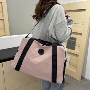 Pink large capacity travel duffel bag with shoulder strap shown carried by a model