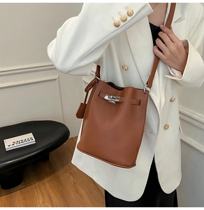 Detailed close-up of brown litchi leather bucket bag featuring silver turn-lock buckle
