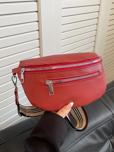 Red lychee grain leather saddle bag with striped shoulder strap and dual zipper detail