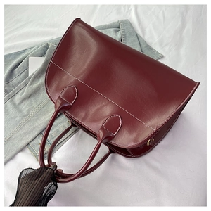 Detailed view of dark red leather tote bag featuring elegant white contrast stitching