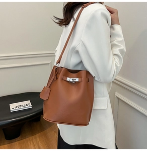 Close-up of brown lychee-grain leather bucket bag with silver buckle and shoulder strap