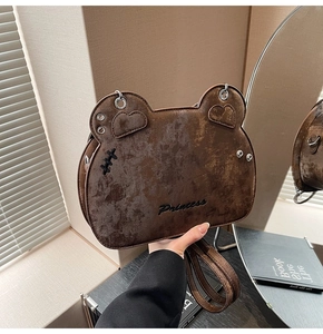 Close-up of vintage brown bear shaped bag featuring Princess embroidery and heart detail