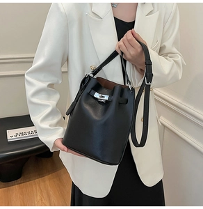 Detail of black lychee grain leather bucket bag featuring a silver twist lock closure