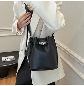 Close-up of black lychee grain leather bucket bag with silver twist lock and strap