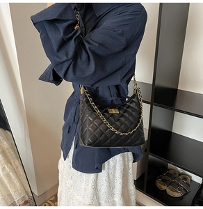 Détail du sac bandoulière noir matelassé avec chaîne dorée porté par un mannequin en style