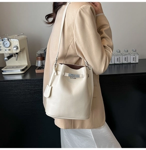 Close-up of cream-white bucket bag with lychee texture and elegant metal twist lock detail