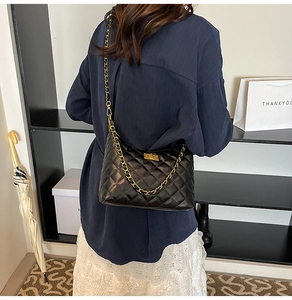 Vue de dos d'un mannequin portant un sac matelassé noir avec une chaîne en métal doré