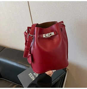Detailed close-up of dark red bucket bag with textured leather and silver rotary lock
