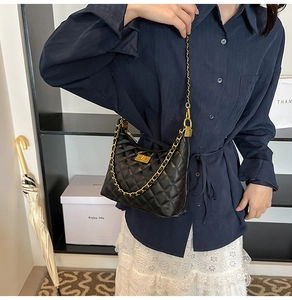 Détail du sac bandoulière en cuir noir matelassé avec chaîne dorée et fermoir pivotant