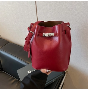 Detailed view of red leather bucket bag with litchi texture and silver buckle