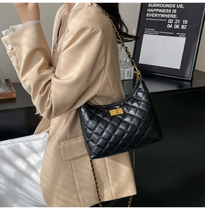 Détail du sac bandoulière noir matelassé avec chaîne dorée et fermoir pivotant carré