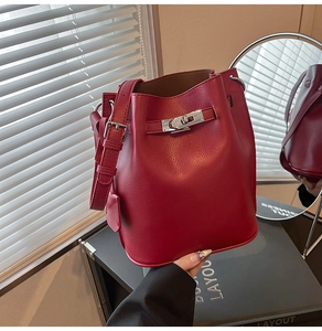 Close-up of red lychee pattern leather bucket bag with silver buckle and adjustable strap
