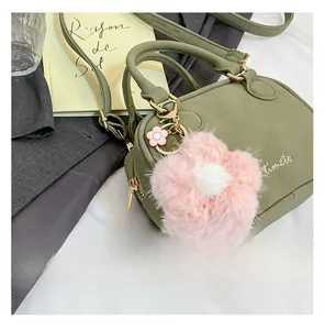 Detail of dark green pillow bag with matte finish and cute pink plush flower charm