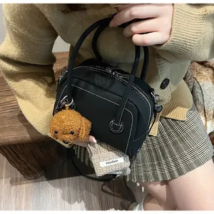 Sac bowling noir avec surpiqûres blanches et charm ours en peluche marron en détail