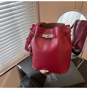Detail of red bucket bag with litchi texture, silver swivel lock and leather strap