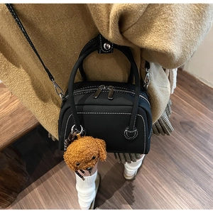 Vue détaillée d'un sac bowling noir avec surpiqûres blanches et pendentif chien peluche