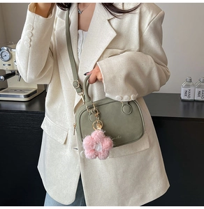 Detail of avocado green suede pillow bag with plush flower charm and strap