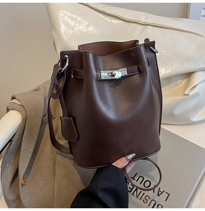 Detailed view of dark brown litchi grain leather bucket bag with silver twist lock closure