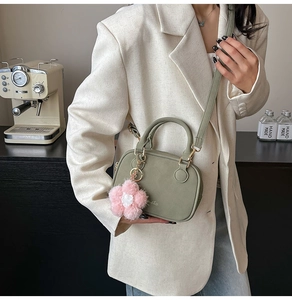 Sage green Boston bag detail with plush flower pendant and crossbody strap setup