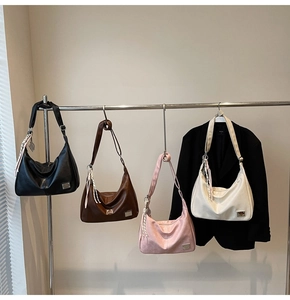 Four bohemian hobo bags in black, brown, pink, and beige hanging on a metal rack