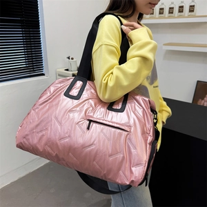 Pink quilted travel duffel bag with black shoulder strap for sports and gym use