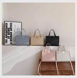 Detail view of five assorted colors of Saffiano leather tote bags with triangle logos