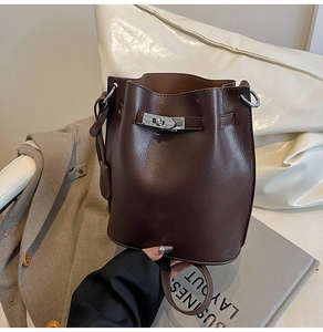 Detail of silver twist lock and litchi grain leather on dark brown bucket bag