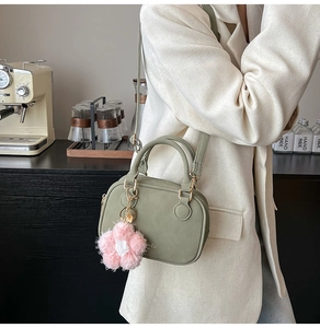 Sage green Boston bag detail with plush flower charm and adjustable shoulder strap