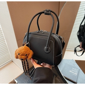 Détail du sac bowling noir avec coutures blanches et breloque chien en peluche