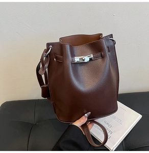 Detail of dark brown lychee grain leather bucket bag with silver twist lock and strap