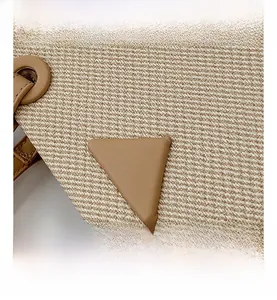 Macro shot of beige woven canvas fabric with triangular leather patch detail on tote bag