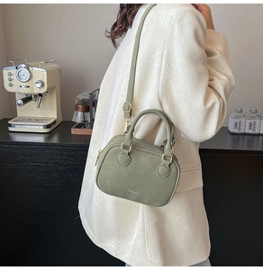 Fashionable sage green crossbody bag with top handles shown in a lifestyle indoor setting