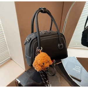 Détail du sac bowling en cuir noir avec surpiqûres blanches et pendentif d'ours en peluche