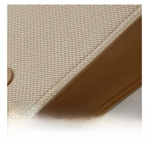 Close-up of beige canvas tote with brown leather trim and precision stitching details