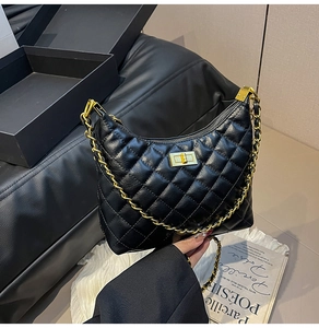 Détail d'un sac hobo noir matelassé avec bandoulière chaîne dorée et fermoir pivotant