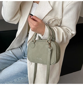 Detail view of sage green matte handbag with timeto logo and golden hardware