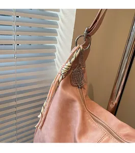 Detail of pink faux leather tote with tennis racket pendant and woven tassel charm