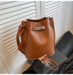 Detail of lychee pattern leather bucket bag with silver metal swivel lock and strap